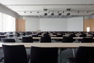 Home Spacious contemporary conference room with rows of tables and chairs, ready for meetings.