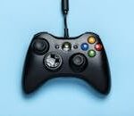 PROYECTOS Black video game controller isolated on a blue background for gaming enthusiasts.