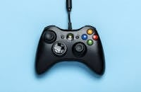 Home Black video game controller isolated on a blue background for gaming enthusiasts.